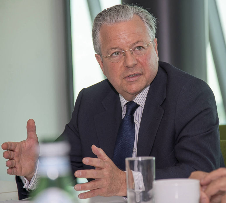 Ein Mann im Anzug sitzt an einem Geschäftstisch und gestikuliert