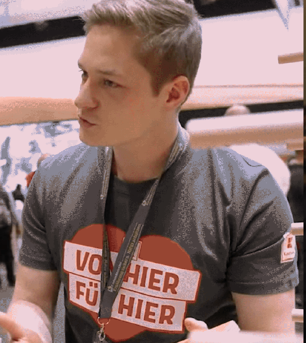 Ein junger, blonder Mann berät an einem Messestand